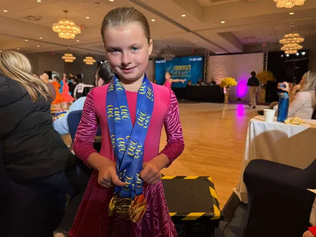 Young VW Dance student wearing gold medals at a ballroom dance competition