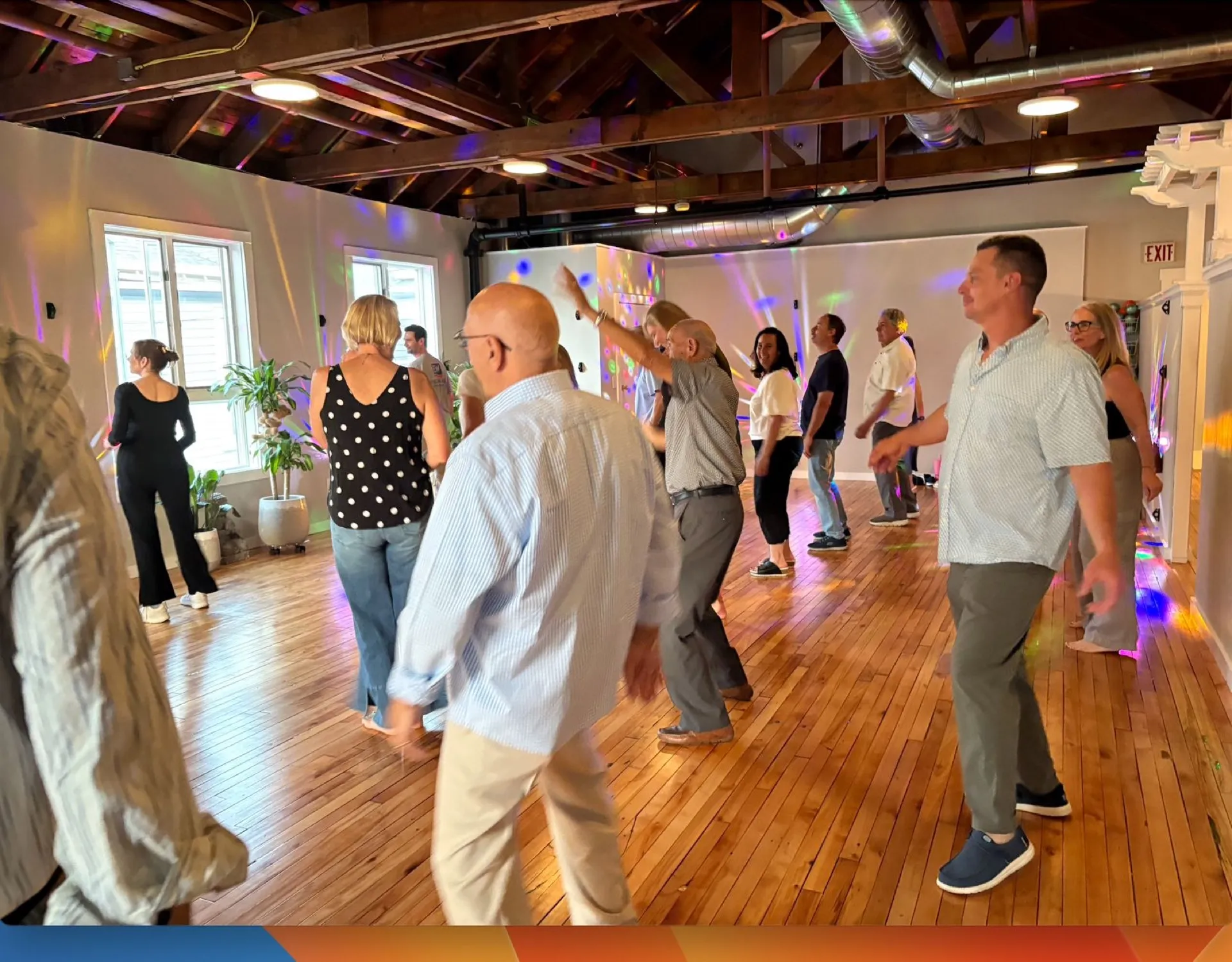 Adults dancing together in a lively group social dance class at the VW Dance studio in South Weymouth